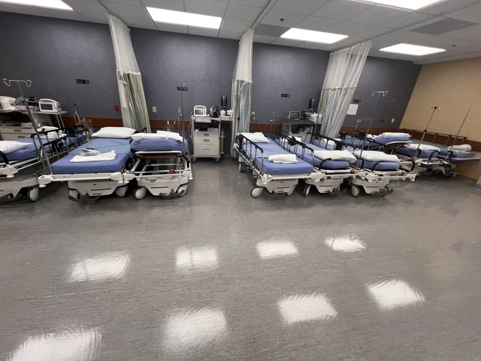 Clinic recovery room with rows of stretchers and a freshly polished vinyl floor
